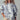Model in Indigo Bloom sweatshirt with ivory floral print and casual cap.