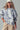 Model in Indigo Bloom sweatshirt with ivory floral print and casual cap.