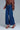 Side angle of indigo wide leg jeans with relaxed fit, paired with flowy blouse and heels
