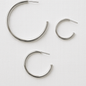 Isabel Hoop Earrings in silver finishes arranged on white fabric background in minimalist flat lay.