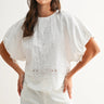 Woman wearing a white blouse with embroidery on a plain background