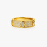 Gold Isola ring with teardrop-shaped diamond on a beige background