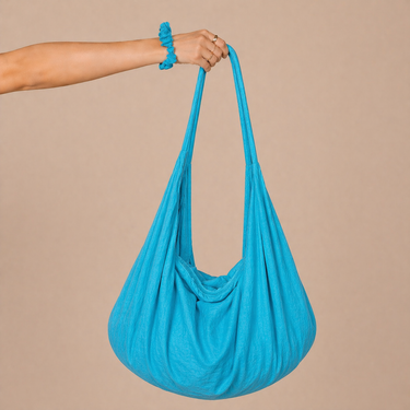 Jaspe Beach Bag in vibrant turquoise cotton with fluid slouchy silhouette and wide strap, designed with a gathered base and soft drape