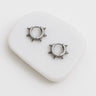 A pair of Juliette stainless steel huggie earrings with a spike design, displayed on a white surface.