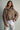 Model wearing the Karls Jacket in taupe, featuring diamond quilting, a padded stand collar, and snap-front closure, styled with light-wash jeans.