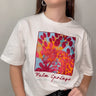 Model wearing the Katerina Tee — white cotton t-shirt with colorful Palm Springs graphic print, relaxed fit, short sleeves, modern casual style.