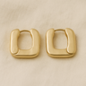 Gold square sculptural huggie earrings on white linen backdrop, Kayden Huggie Earrings.