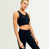 Woman wearing a black sports bra and leggings with star designs on a light gray background
