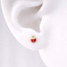 Ladybug Stud Earrings worn on ear featuring glossy red enamel ladybug design with black detailing and gold accents, shown on a model ear against a soft neutral background, small dainty everyday stud earrings.
