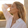 Chunky gold oval link necklace styled on model with open white shirt, polished reflective finish, and luxury editorial jewelry styling