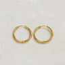 Linea Huggie Earrings, slim gold huggie hoop earrings with smooth polished finish, photographed on white linen background with soft editorial lighting.
