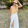Luli Linen Tank Top mustard sleeveless linen top styled with a white skirt, outdoors full front view.