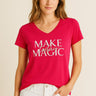 Woman wearing the vibrant pink Magic Tee with silver “Make today Magic” lettering, paired with white jeans against a neutral background.
