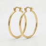 Slim polished gold hoop earrings with a sleek lightweight design and secure hinge closure on a soft neutral background - Matte Jewelry
