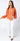 Maréa Blouse full body outfit styled with white trousers, showcasing bold sunset-orange color, button-up front, and airy relaxed fit, perfect for vacation dinners and summer resort styling.