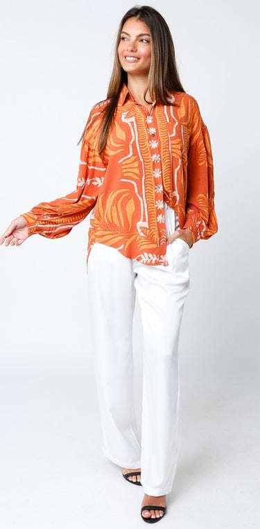 Maréa Blouse full body outfit styled with white trousers, showcasing bold sunset-orange color, button-up front, and airy relaxed fit, perfect for vacation dinners and summer resort styling.