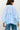 Light blue checkered blouse with ruffled details worn by a person on a plain background