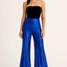 Model wearing electric blue metallic pants with black top and boots, front view.
