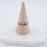 A clip ring with gold plated design displayed on a beige conical stand.