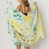 Woman wearing Matera Sarong in yellow and green abstract print, draped as a beach wrap.