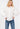 Model wearing the Meredith Blouse in white — cotton button-down with voluminous sleeves, styled with blue jeans against a white background.