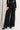 Model in Midnight Lace Pants showing high-rise satin waistband and wide-leg lace silhouette, paired with black heels.