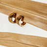 A close-up image of a pair of Mila gold-plated hoop earrings on a wooden surface.