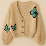 Mirka Sweater in beige knit with blue butterfly embroidery displayed on a neutral background.