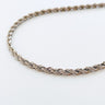 A gold-plated necklace with a rope chain design, laid out on a plain surface.