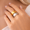 Close-up of a hand wearing a gold and silver ring on a neutral background by matte jewelry 