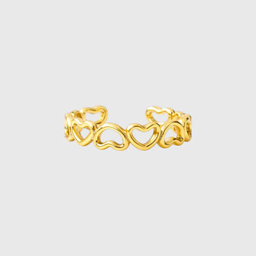 Gold-plated ring with interlocking heart design displayed on marble background