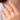 Gold ring with a unique design on a person's finger against a neutral background