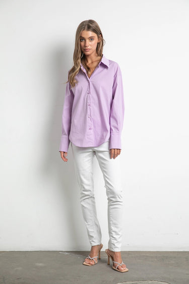 Model styled in Noema Lilac Shirt with white jeans and nude heels.
