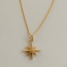 Close-up of Nova Necklace showing polished gold star pendant and delicate chain.