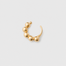 Gold ear cuff with spherical beads on a light gray background