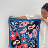 Periwi Scarf in periwinkle blue, pink, and coral abstract print, silky square scarf held by model in white dress, Matte Wrap It Up collection.
