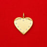 Pola Pendant gold heart charm with clear zirconia stones on a polished surface, photographed on a bold red background