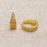 Poli Huggie Earrings, gold huggie hoop earrings with tapered pavé-set design and polished mirror finish, photographed on white linen background with soft editorial lighting.
