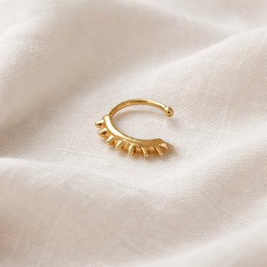 Pordenone Ear Cuff in gold with seven spikes, worn on a model’s ear, minimalist statement design with a polished finish on a neutral background.