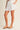 Ragit Short white high-waisted pleated shorts side view showing fluid drape and airy lightweight fabric for resort wear.