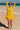 Ray Cover Up lightweight yellow beach cover-up with relaxed flowy silhouette, long sleeves, and deep V neckline, worn over swimwear on the beach.