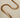 A gold-plated necklace with a herringbone chain design laid out on a plain surface.