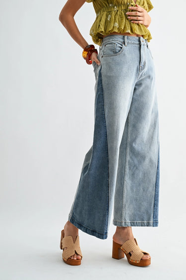 Person wearing light blue wide-leg jeans and a yellow top on a white background