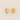 Gold heart-shaped Romy earrings on a beige fabric background