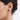 Close-up of an ear wearing a blue square stud earring with a blurred background from Matte.