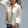 Silky champagne button-down shirt with fluid drape and long sleeves, shown on model styled with dark denim — Sandora Shirt by Matte.
