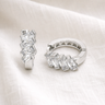 Satori Huggie Earrings – huggie earrings with clear crystal stone detailing, photographed on a soft neutral fabric background.