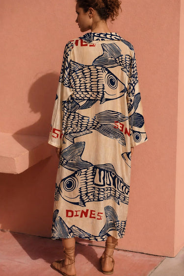 Seaside Dress shown on model, featuring a relaxed flowy silhouette, short sleeves, and bold coastal-inspired print in neutral and navy tones, back view.