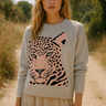 Woman wearing a sweater with a pink leopard design in a natural setting