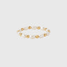 A gold-filled stretch ring with polished gold beads and pearls displayed on silver backdrop